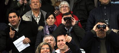 Espectadores siguiendo las carreras en las tribunas del hipódromo con prismáticos para ver mejor la recta opuesta.