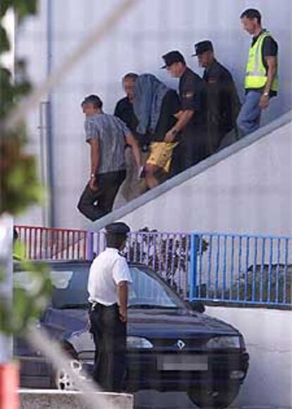 Agentes de la policía sacan detenido a Alexander King, con el rostro cubierto, de su casa en Alhaurín el Grande (Málaga).