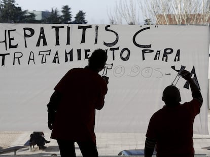 Dos personas teminan de pintar un cartel sobre un cristal en el Complejo Hospitalario de Navarra donde las alrededor de treinta personas que se encuentran desde el mediodía de ayer han decidido por ahora mantener su encierro hasta tanto no estudien con especialistas sanitarios y legales el documento entregado por la consejera Marta Vera en relación con el tratamiento de la hepatitis C. EFE/Jesús Diges