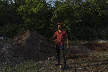 Um homem segura uma estrutura de madeira utilizada para fabricar tijolos com sargaço. Omar Vázquez criou uma pequena empresa que produz blocos tendo a alga como matéria prima.