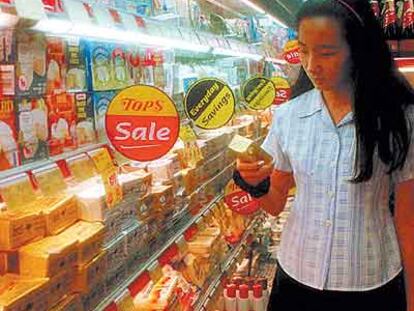 Una mujer mira las estanterías de mantequilla y lácteos en un supermercado de Bangkok.