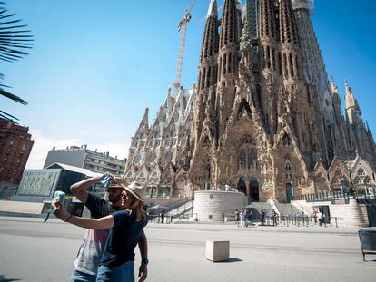 Una pareja se fotografía ante una Sagrada Familia casi vacía en Barcelona.