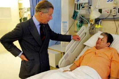 El príncipe Carlos de Inglaterra conversa con un herido ingresado en el hospital St Mary's.