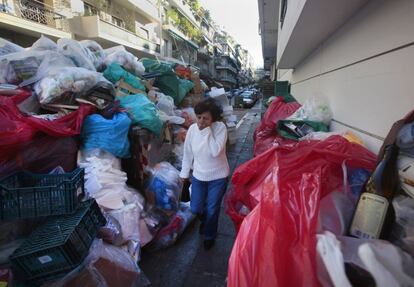Una mujer tapa su nariz al paso de la basura amontonada por la huelga en una de las calles de la capital griega.