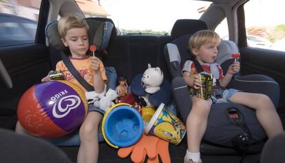 Dos nens viatgen asseguts a les cadires adaptades a la part posterior d'un cotxe.