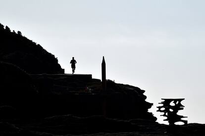 Un hombre corre frente a las esculturas 'Filtro', del artista italiano Maurizio Perron, y 'Más de lo que parece', del brasileño Geraldo Zamproni, este jueves frente a la playa Bondi de Sídney (Australia).