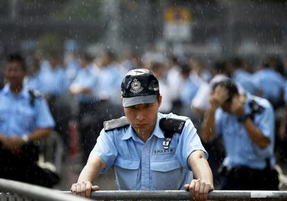 Los altercados han ocurrido en la zona comercial local de Mong Konk, el barrio más denso, y en Causeway bay, donde suelen acudir los turistas chinos del continente a realizar sus compras en esta época del año, una semana festiva en el país asiático. En la imagen, un policía permanece bajo la lluvia mientras manifestantes se concentran frente a edificios gubernamentales, en el sexto día de protesta en Hong Kong.