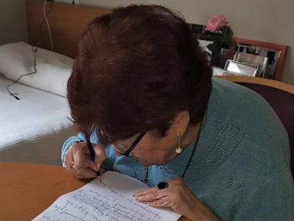 Una mujer contesta una carta en una residencia de mayores.