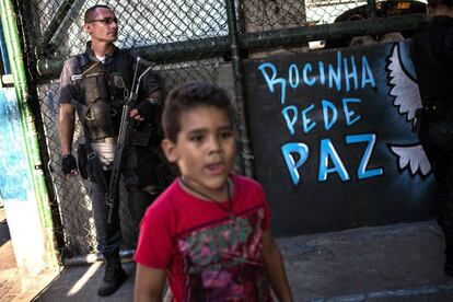 Uma criança e um policial na quadra onde moradores da Rocinha pediram à volta da sua rotina.