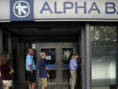 Varias personas esperan para hacer alguna gestión en una de las oficinas del bancogriego Alpha Bank.