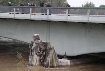 Parisencs observant una estàtua del Pont de l'Alma, coberta per l'aigua del Sena.