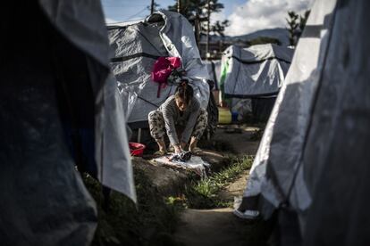 Unos grandes depósitos de agua, con restricciones de horario, surten de agua a la población del campamento. Una mujer lava la ropa al atardecer entre las tiendas del campamento de refugiados.