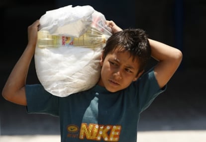 Un menor carga con un saco de comida en el campo de refugiados de Shati, en Ciudad de Gaza