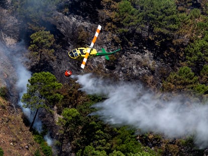 Un helicóptero sigue trabajando en la extinción del incendio forestal en Pujerra (Málaga) el pasado viernes.