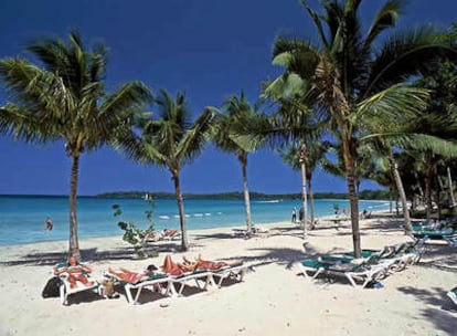 Turistas bajo palmeras en Bloody Bay Beach, una de las playas más largas de Jamaica