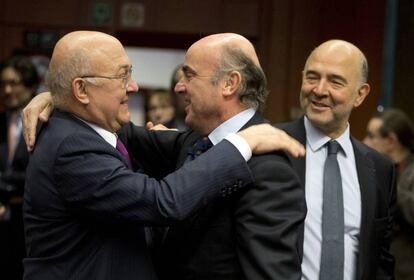 El ministro francés de Finanzas, Michel Sapin, saluda al español Luis de Guindos. A la derecha, el comisario Pierre Moscovici