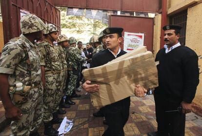 Un policía lleva las papeletas a un colegio electoral de El Cairo, custodiado por un grupo de militares.