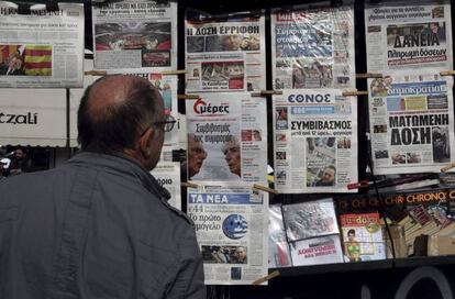 Un hombre observa portadas de peri&oacute;dicos en un kiosco de Atenas.