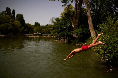 Un joven salta al río Arga para refrescarse durante la ola de calor en Pamplona este 9 de agosto.