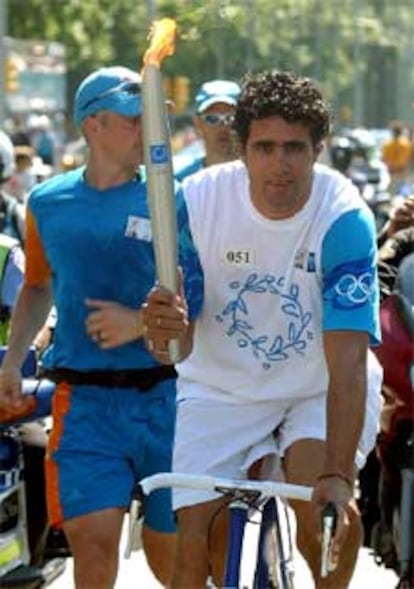 Miguel Indurain, en bici, con la antorcha por las calles de Barcelona.