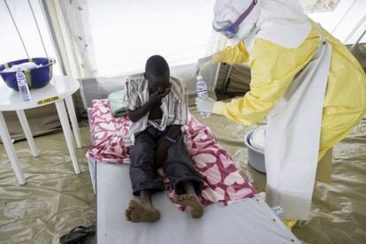 Un médico da agua a un paciente ingresado en la zona de aislamiento.