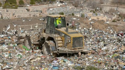 Una excavadora compacta la basura en el vertedero.