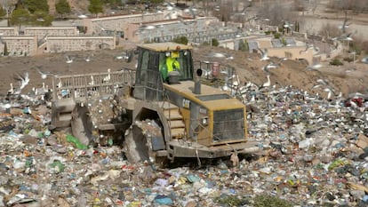  Una excavadora compacta la basura en el vertedero.