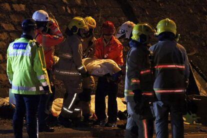 Los equipos de rescate apartan un cuerpo tras el accidente de autobús este sábado en Hong Kong.