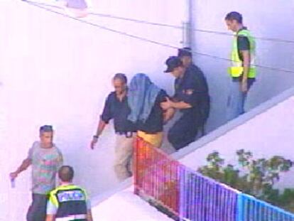 Imagen de la televisión que muestra al detenido acompañado por la policía a la salida de su domicilio.