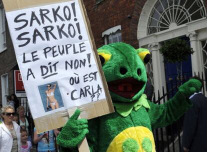 Un manifestante disfrazado de rana gigante porta un cartel que reza: "Sarko, Sarko la gente ha dicho no. ¿Dónde está Carla? en las protestas registradas hoy en Dublín