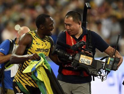 Usain Bolt habla con el cámara que le atropelló mientras celebraba su victoria en los 200 metros lisos.