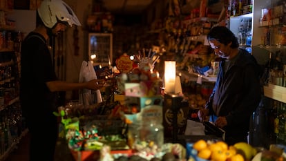 Un comerciante trabaja con la ayuda de velas y una linterna en el barrio de la Bórdela de Barcelona, el 28 de abril.