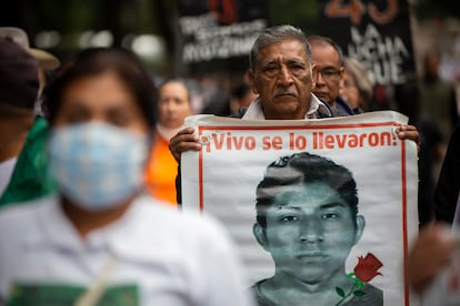 Un hombre carga la imagen de uno de los 43, durante una manifestación en Ciudad de México, el 26 de agosto de 2022.