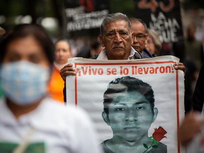 Un hombre carga la imagen de uno de los 43, durante una manifestación en Ciudad de México, el 26 de agosto de 2022.