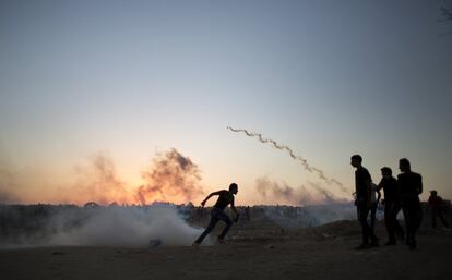 Manifestantes palestinos corren a protegerse del gas lacrimógeno disparado por soldados israelíes durante los enfrentamientos en la frontera de Israel con Gaza en Buriej, Franja de Gaza.