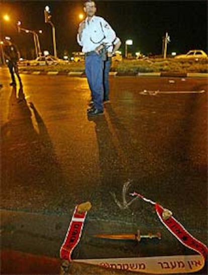 Un policía israelí permanece junto al cuchillo empleado por el agresor.