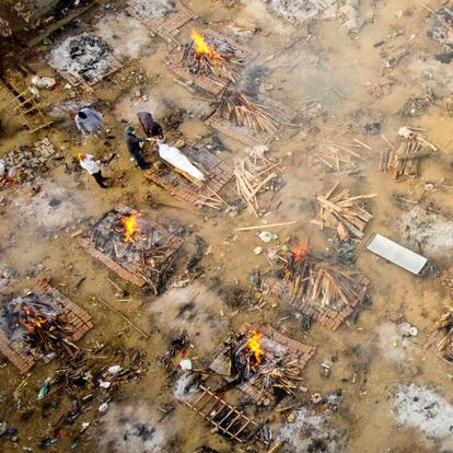 In this aerial picture taken on April 26, 2021, relatives and friends of a victim who died of the Covid-19 coronavirus gather to cremate the body at a cremation ground in New Delhi. (Photo by Jewel SAMAD / AFP)