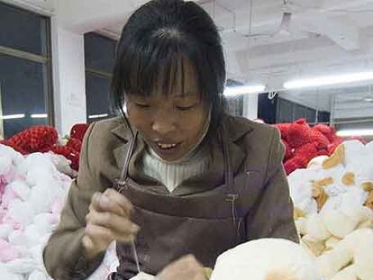 Una mujer china cose muñecos de peluche en un taller chino.