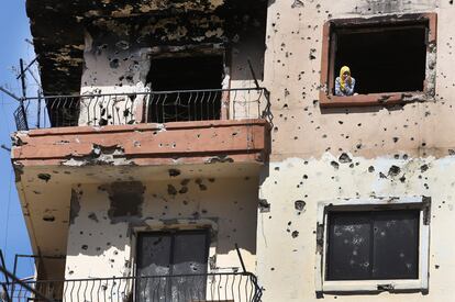 Una mujer mira por la ventana de su casa dañada por disparos en la ciudad de Trípoli (Líbano).