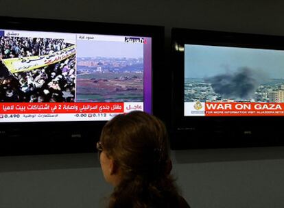 Una mujer observa dos pantallas que emiten Al Yazira
