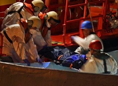 En el cayuco interceptado por la Guardia Civil viajaban 52 personas. Los efectivos de Salvamento Marítimo descienden el cadáver de uno de ellos.