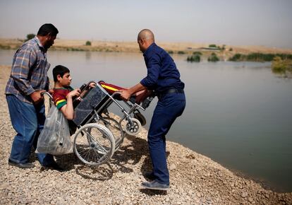 Iraquíes desplazados intentan cruzar el río Tigris con un discapacitado mientras las fuerzas iraquíes luchan contra militantes del Estado Islámico en el oeste de Mosul, Irak.