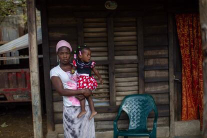 "El dinero que me dieron no es suficiente para volver a tener una casa", cuenta Lidna Dorfinis, una haitiana de 38 años residente de La Mara. Le pagaron 250.000 pesos (unos 4.500 dólares), que apenas alcanzan para un terreno. Sin recursos para comprar material de construcción, esta madre de tres hijos paga 60 dólares mensuales de alquiler. En la imagen, Lidna Dorfinis posa para un retrato con una de sus hijas en brazos.