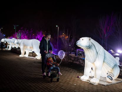 Un padre con su hijo en un carro observa una escultura iluminada de un oso, el viernes tras la inauguración de Árticus.