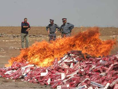 Dos gendarmes observan cómo arde un alijo de tabaco.