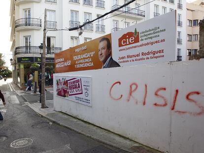 Un hombre pasa junto a un cartel electoral de un grupo independiente de Estepona.