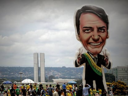 Seguidores del presidente electo, Jair Bolsonaro, caminan frente a un muñeco gigante con su figura en la Explanada de los Ministerios.