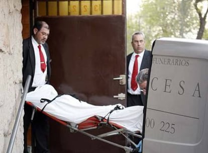 Dos operarios retiran el cadáver del hombre asesinado ayer por su padre.