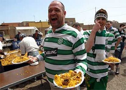 Aficionados del Celtic recogen un plato de paella preparada por un restaurante de Vila-real.