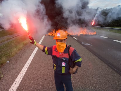 Un trabajador de la planta de Alcoa San Cibrao enciende una bengala durante una protesta ayer en la autovía A6 en Outeiro de Rei (Lugo).